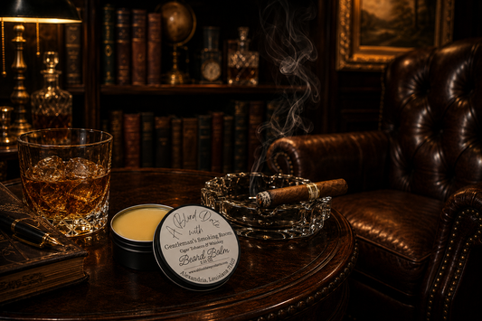 Luxury lifestyle image for A Blind Date Gentleman's Smoking Room Beard Balm. An open tin of smooth beard balm with the original product label sits on an elegant dark wood table beside a crystal glass of whiskey with ice, a lit cigar resting in a glass ashtray, and a leather-bound journal with a fountain pen. Warm lighting, rich leather furniture, dark wood bookshelves filled with classic books, and a decanter in the background create the refined atmosphere of a sophisticated gentleman's smoking room, highli